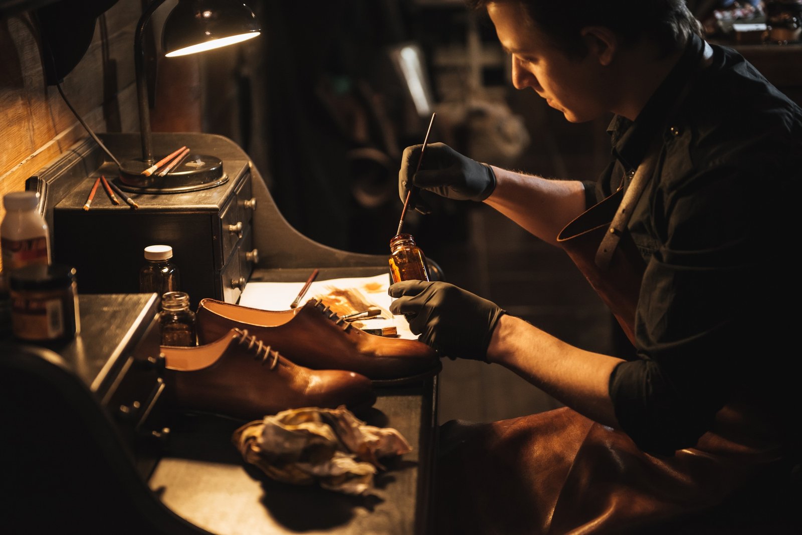 Young concentrated man shoemaker at footwear workshop.